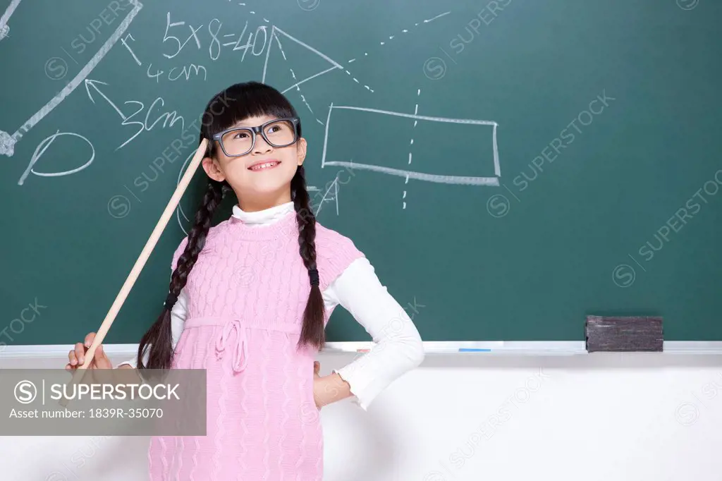 Humorous little girl playing teacher in classroom