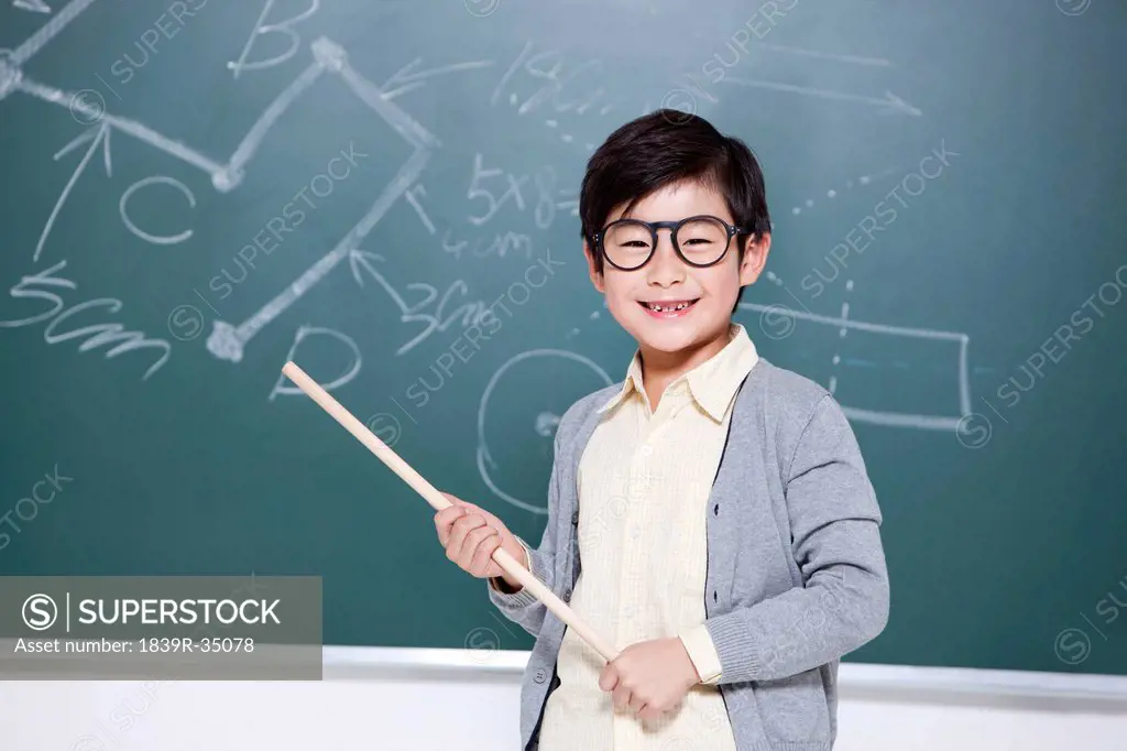 Active little boy playing teacher in classroom