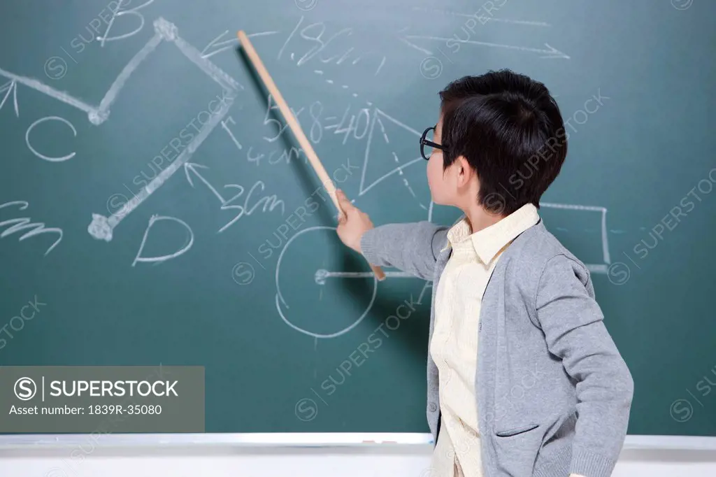 Active little boy playing teacher in classroom