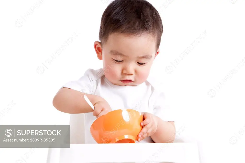 Cute baby boy with spoon and bowl