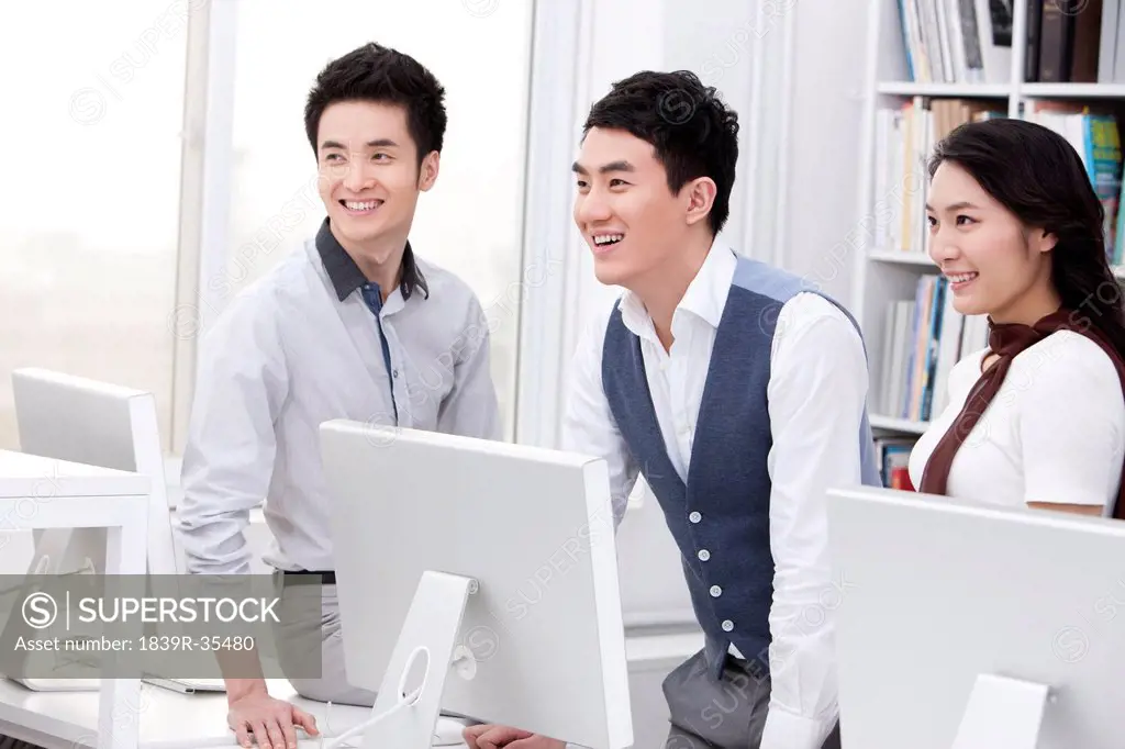 Cheerful office workers using computers in studio