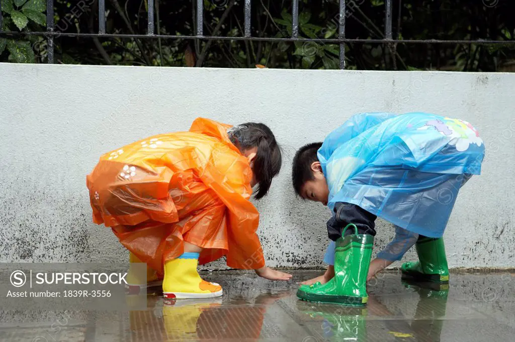 Young Children In The Rain With Raincoats