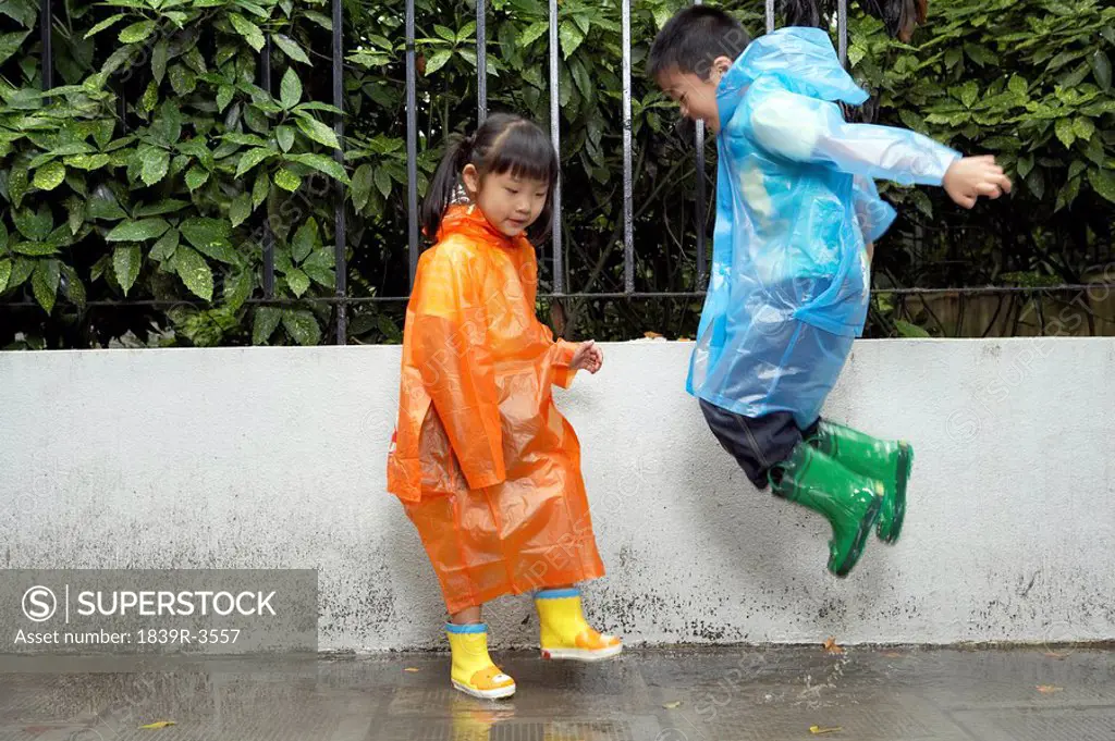 Young Children In The Rain With Raincoats