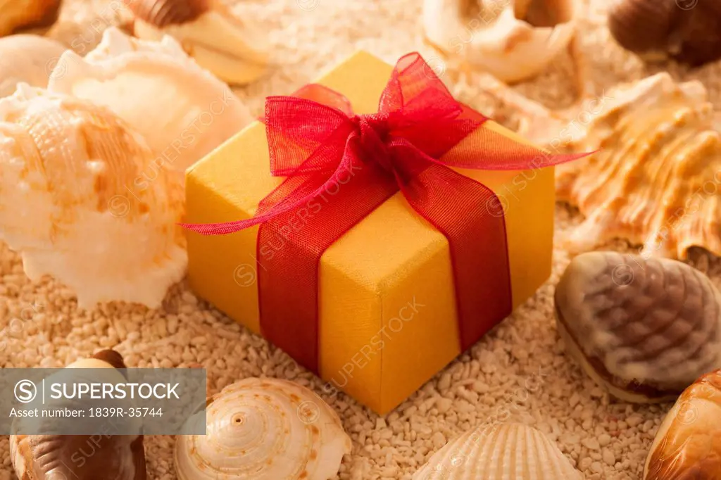 Shell and gift box in sand