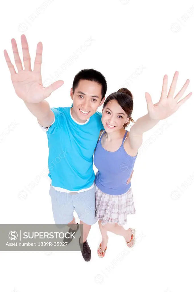 Happy young couple raising hands