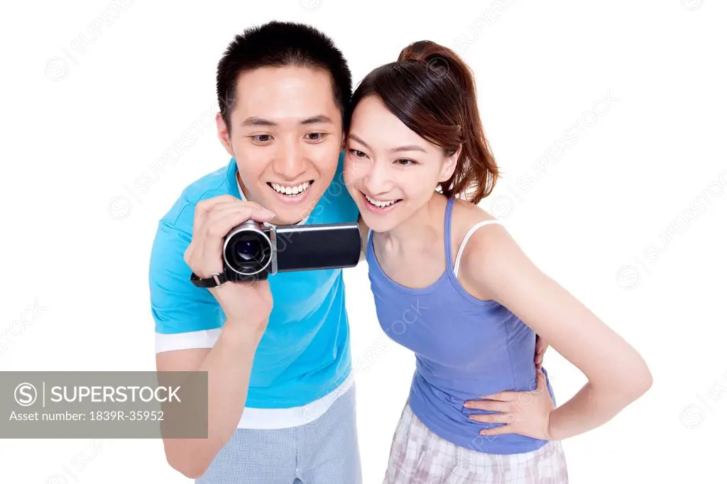 Happy young couple photographing with home video camera