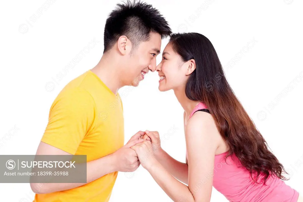 Happy young couple holding hands, face to face
