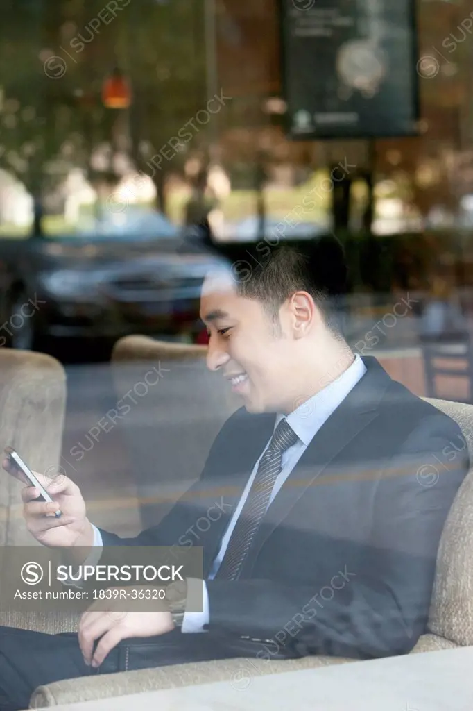 Happy businessman with smart phone in cafe