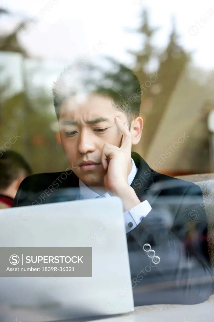 Serious businessman using laptop in cafe