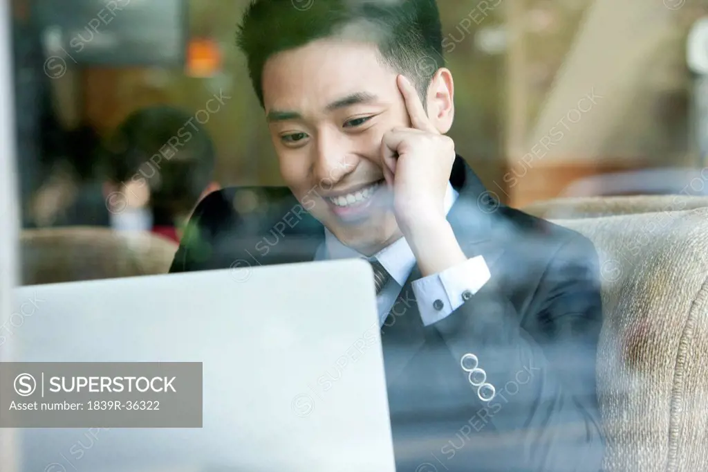 Happy businessman using laptop in cafe