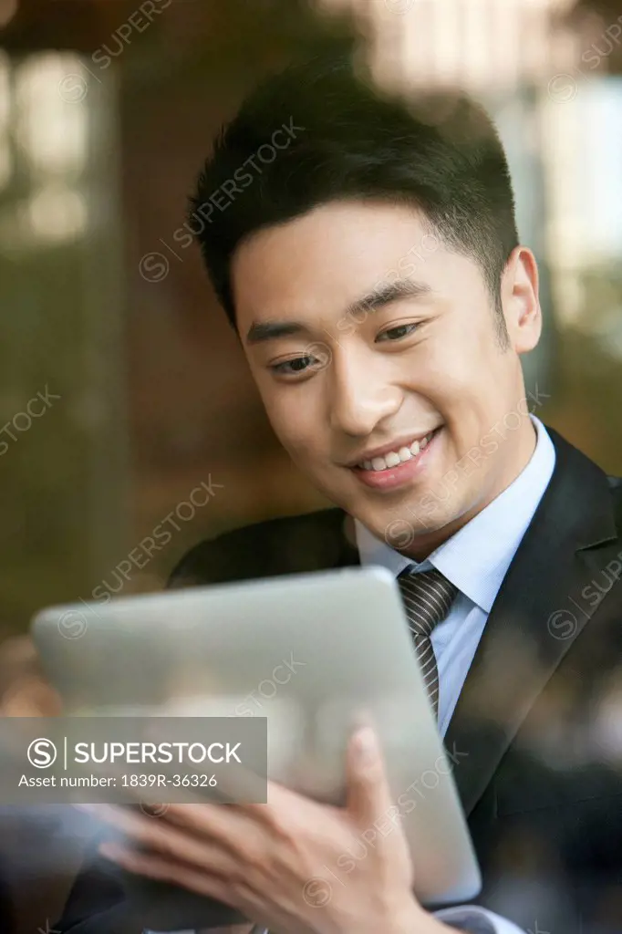 Businessman playing digital tablet in cafe