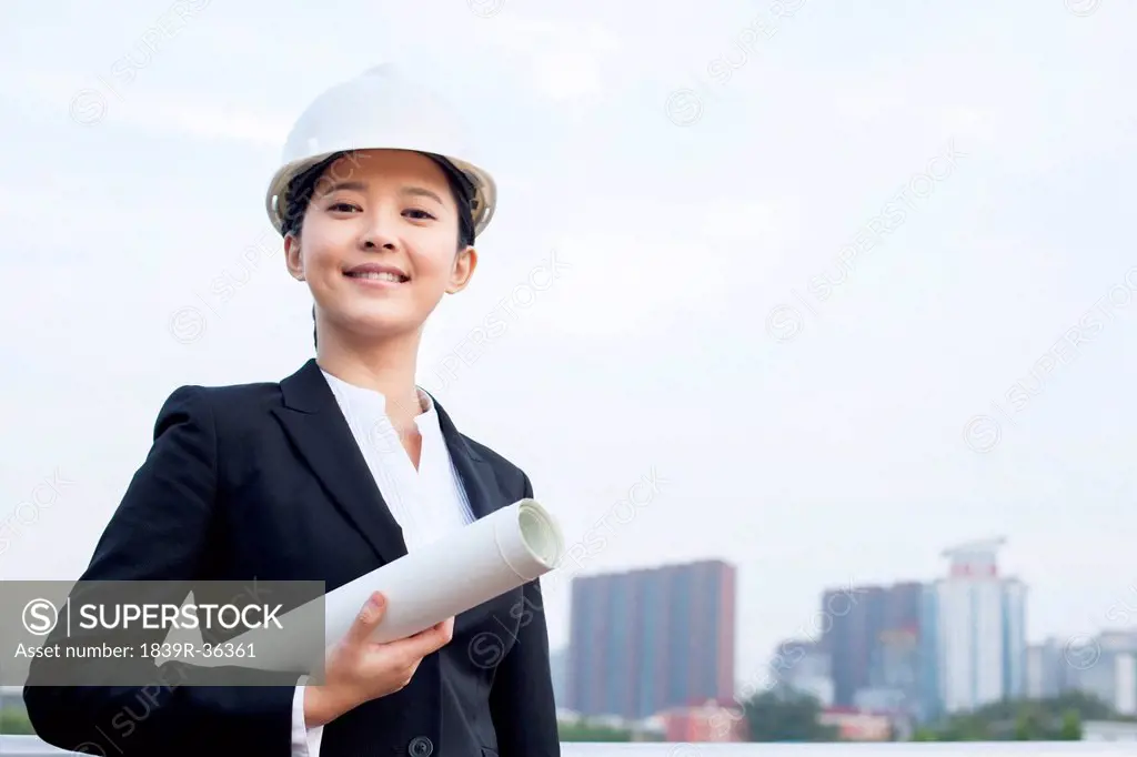Young female architect with blueprint outdoors