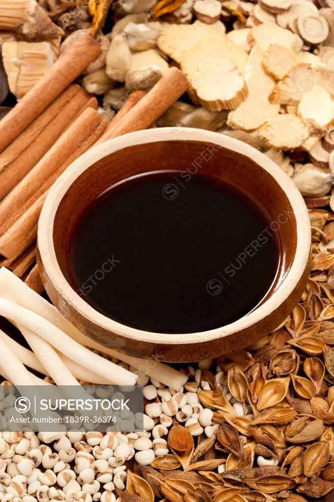 Various Chinese herbal medicine with a bowl of herbal liquid medicine