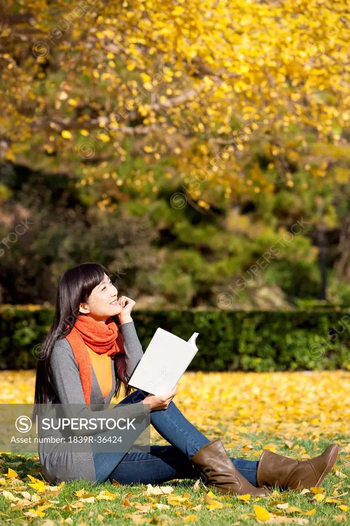 Young woman reading books in beautiful autumn day