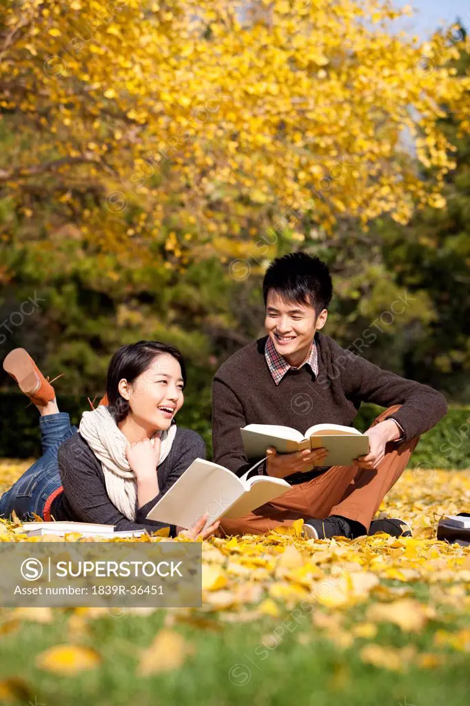 Merry college couple with books in the golden autumn on campus