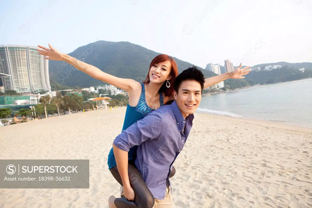 Sweet young couple playing piggyback on the beach of Repulse Bay, Hong Kong