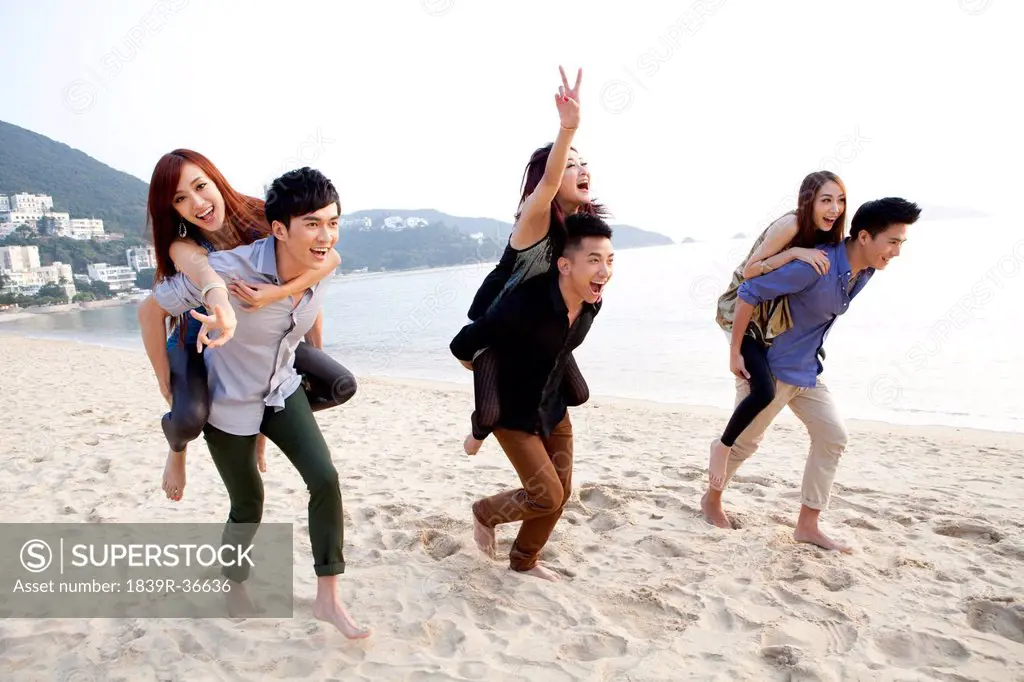 Excited young people playing piggyback on the beach of Repulse Bay, Hong Kong