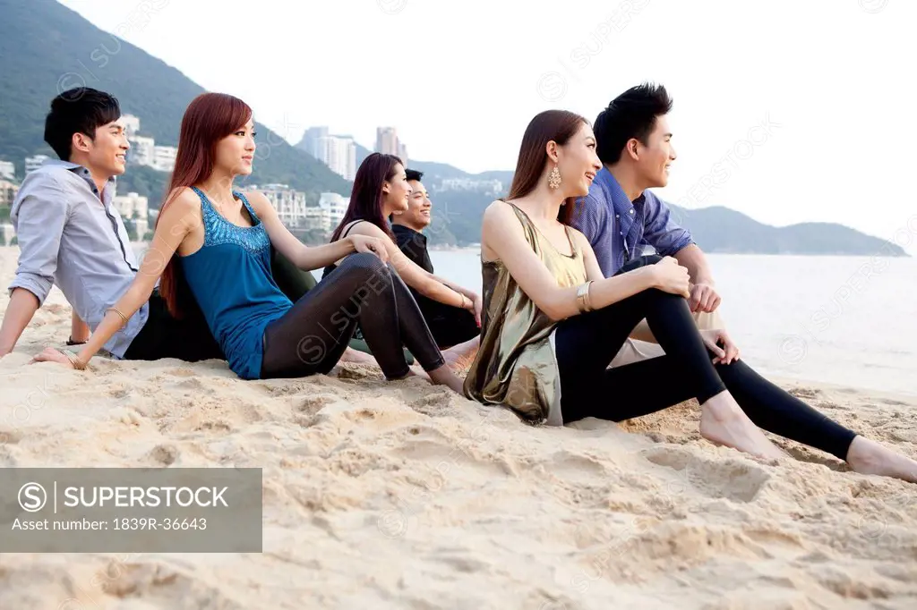 Happy young people sitting on the beach of Repulse Bay, looking at view, Hong Kong