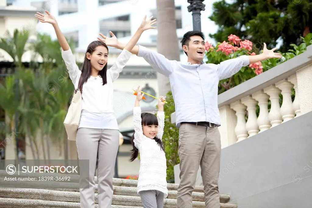 Happy young family arms raised on steps in Hong Kong