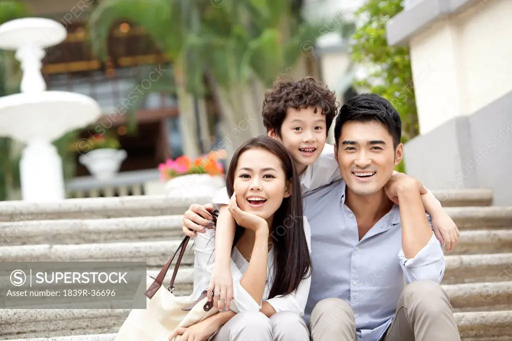 Happy young family sitting on steps in Hong Kong