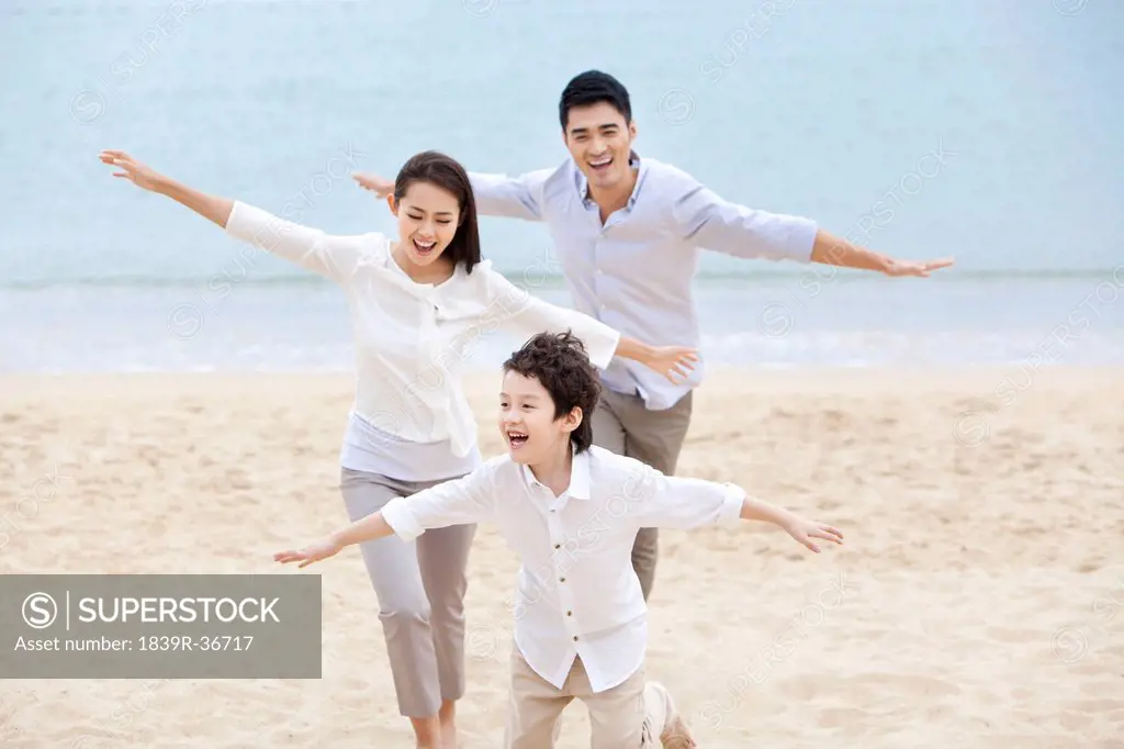 Joyful young family pretending to be flying on the beach of Repulse Bay, Hong Kong