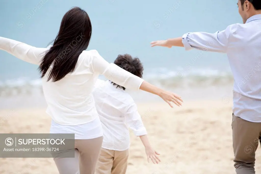 Happy young family pretending to be flying freely on the beach of Repulse Bay, Hong Kong