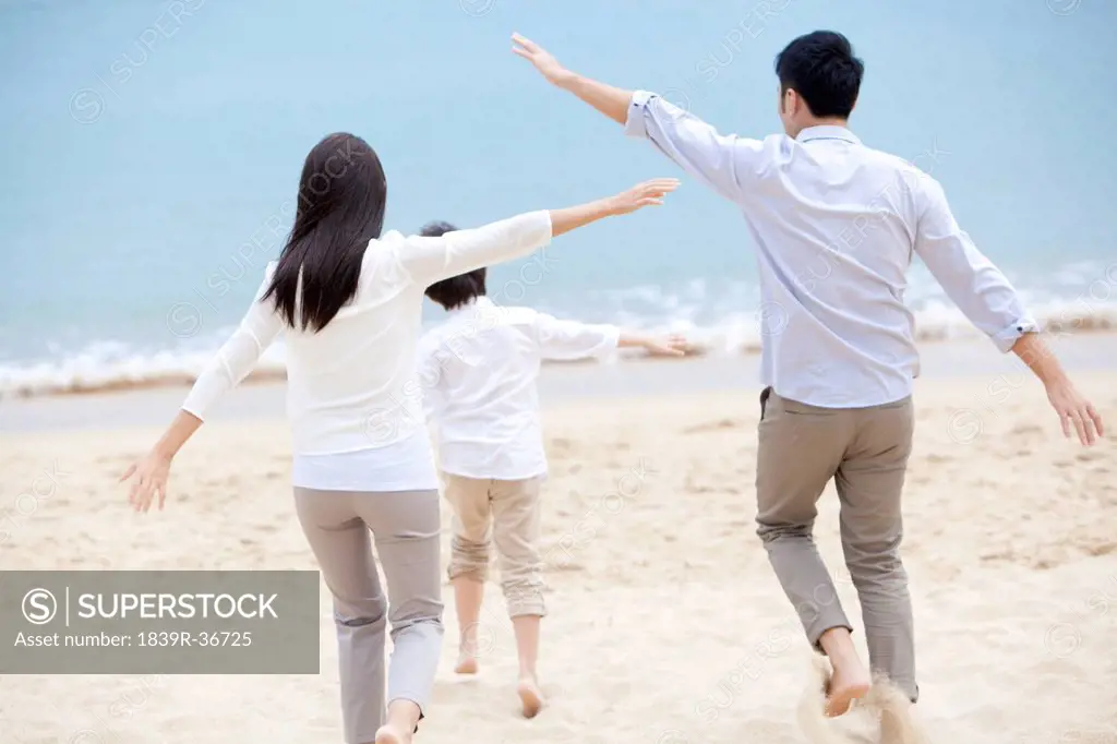 Happy young family pretending to be flying freely on the beach of Repulse Bay, Hong Kong