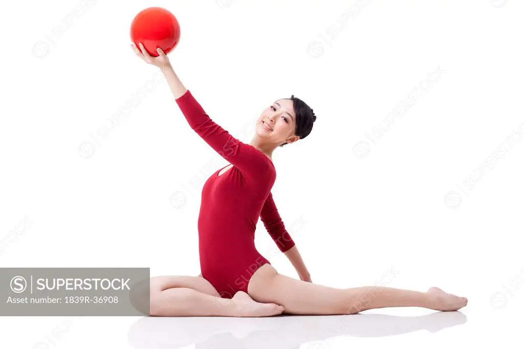 Female rhythmic gymnast performing with ball