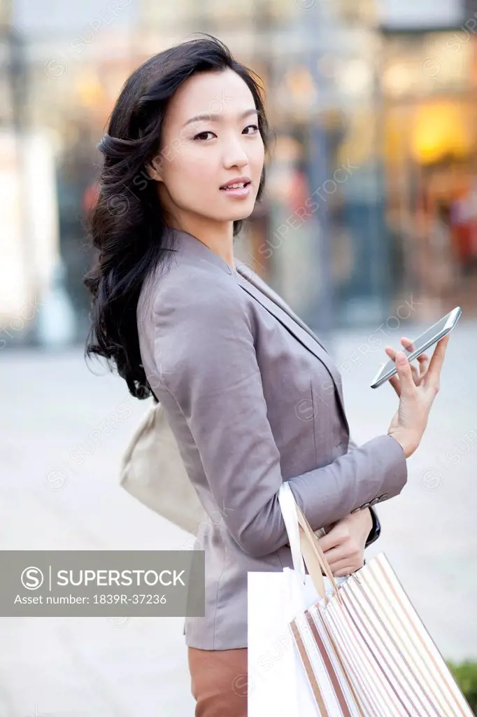 Happy young woman with shopping bags and smart phone