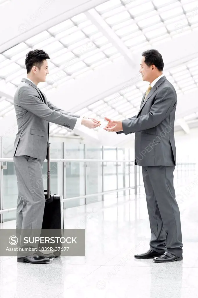 Business associates exchanging business card in airport lobby