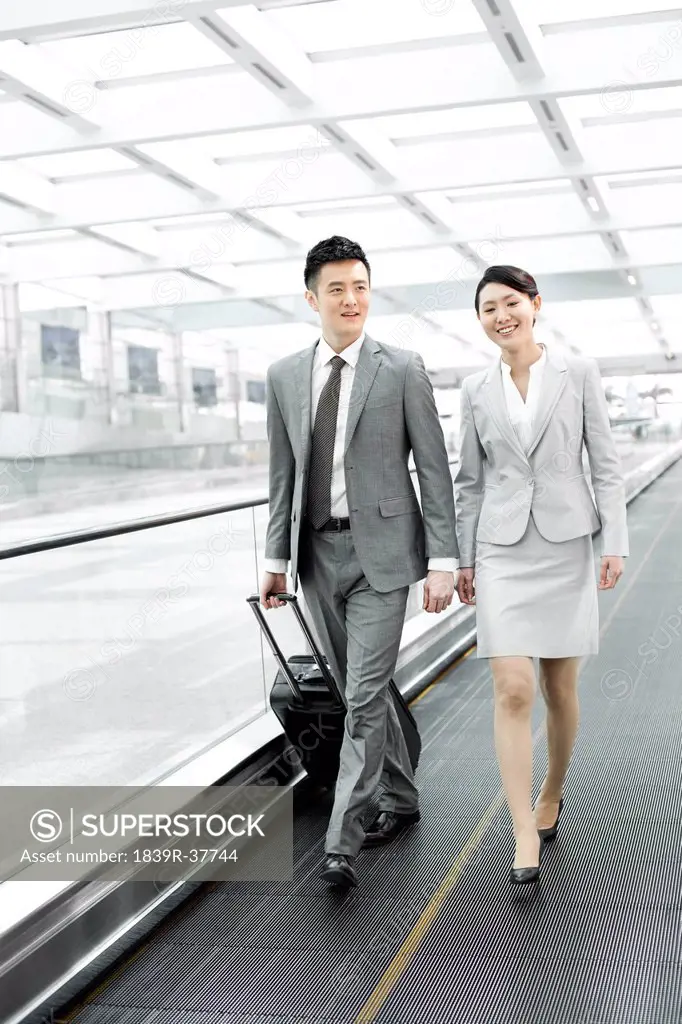 Business colleagues with luggage on airport escalator