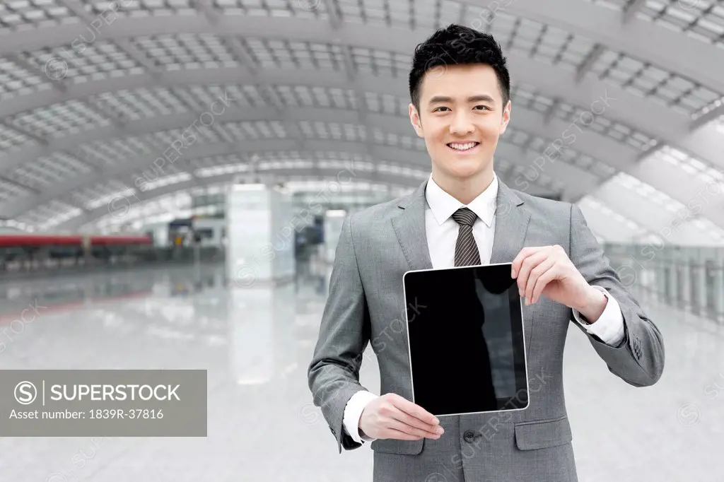 Young businessman showing digital tablet at the airport
