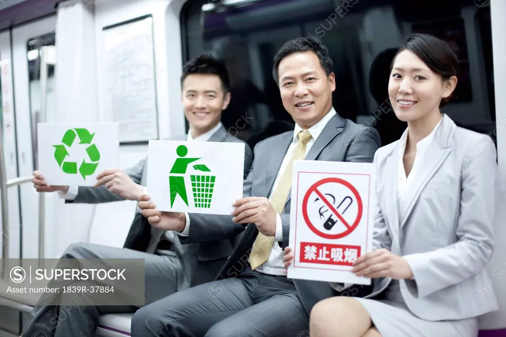 Business persons holding various kinds of sings in subway train