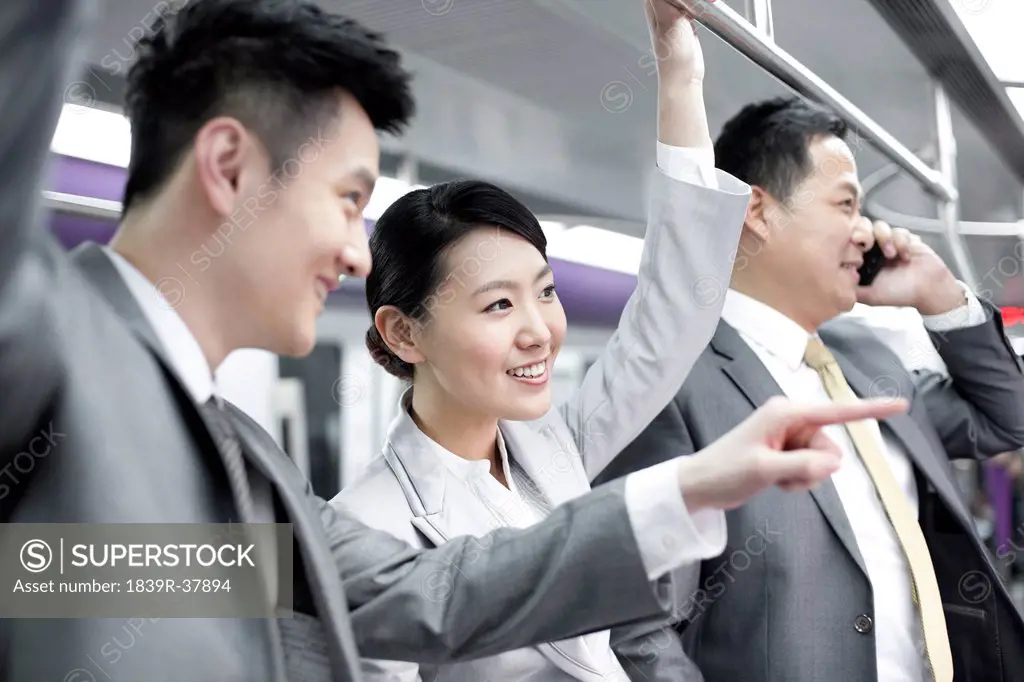 Cheerful business persons pointing outward in subway train