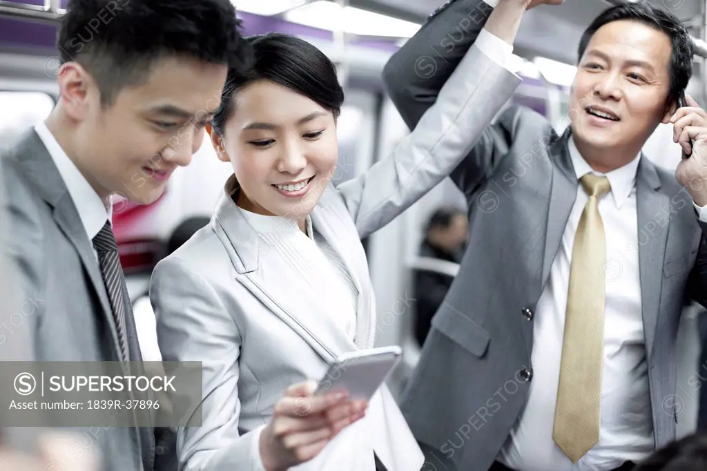 Cheerful business persons with mobile phone in subway train