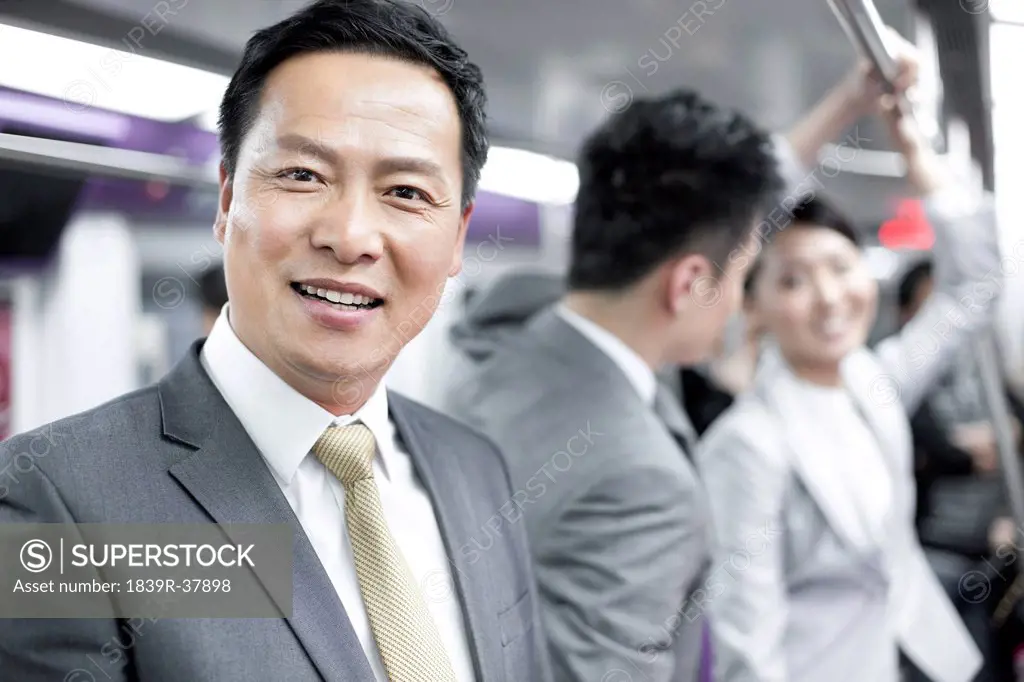 Cheerful businessman with partners in subway train