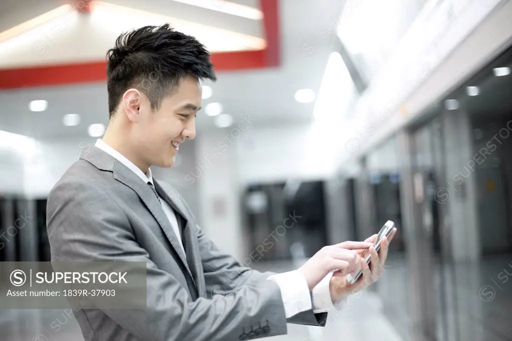 Young businessman with mobile phone on subway platform