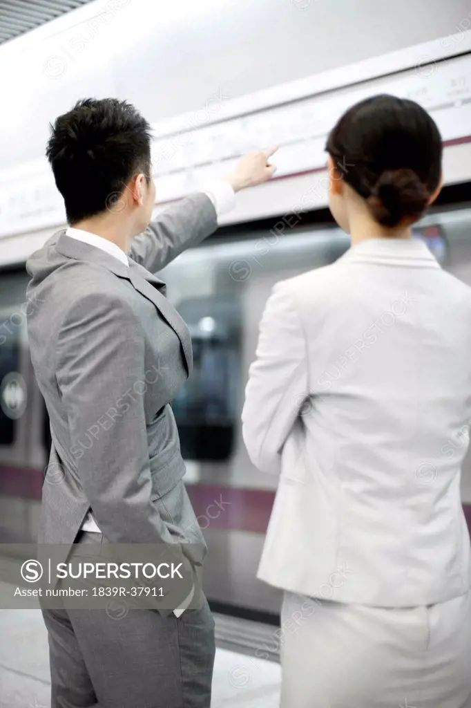 Young businessman showing the way to businesswoman on subway platform