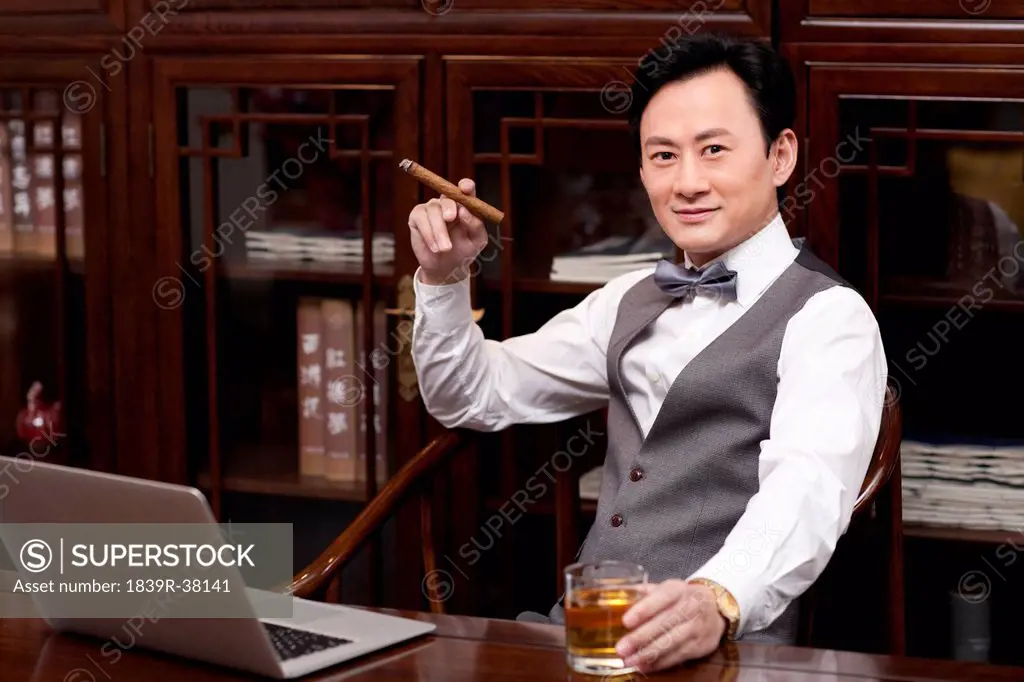 Successful businessman with cigar and drink in hands