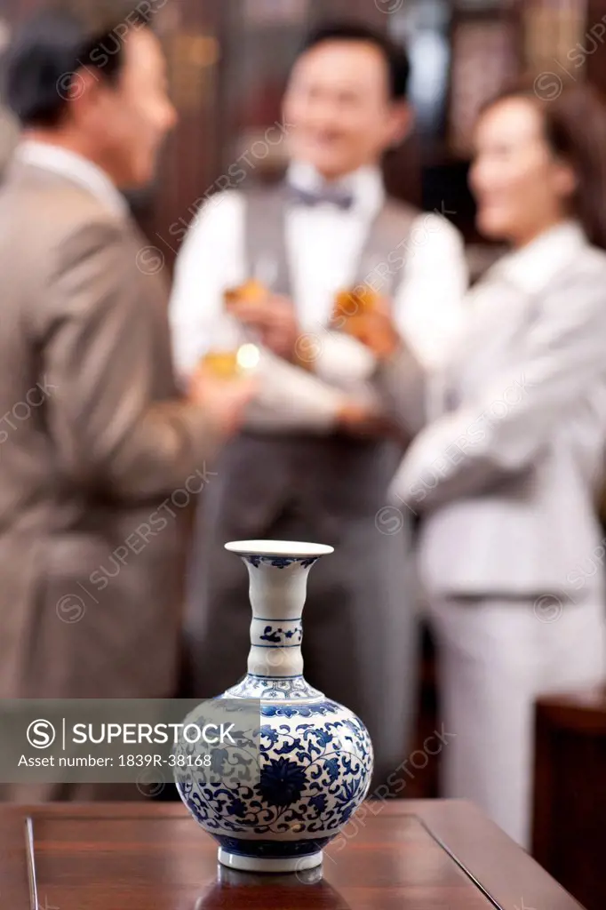 Close up of precious vase with business people in background