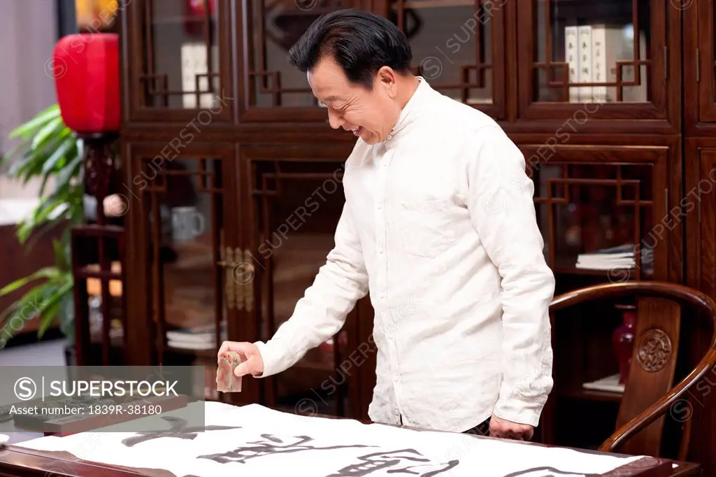 Senior man practicing calligraphy in the study