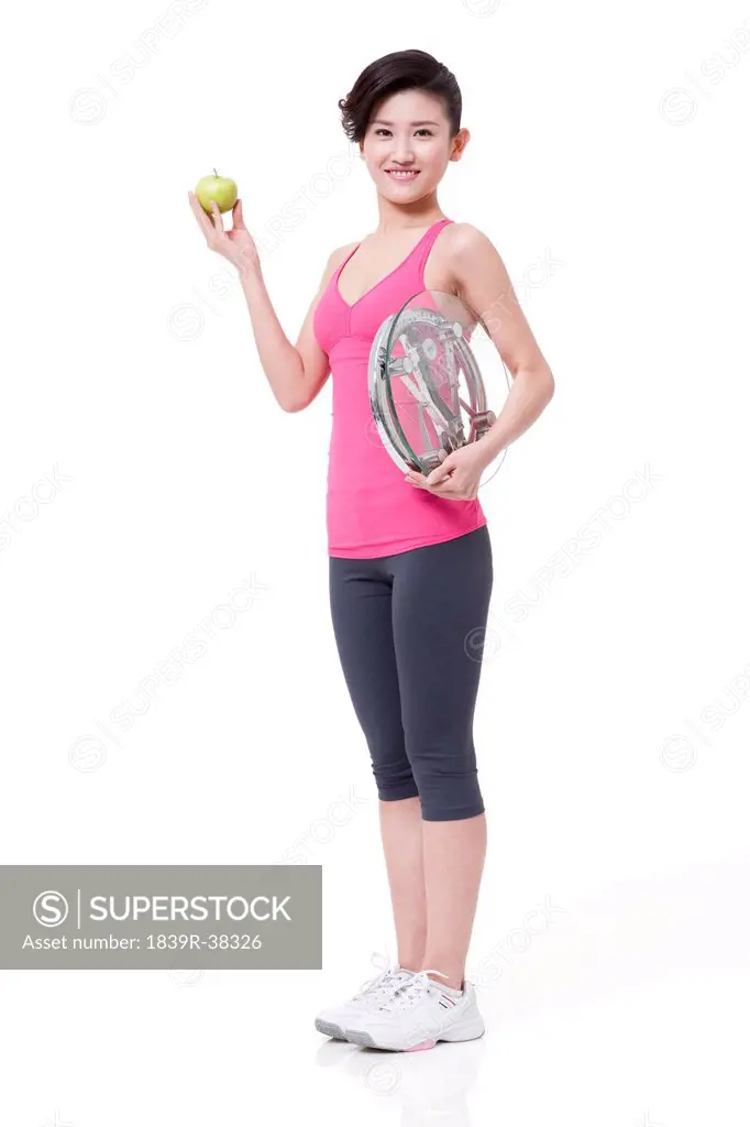 Slim young woman with apple and bathroom scale
