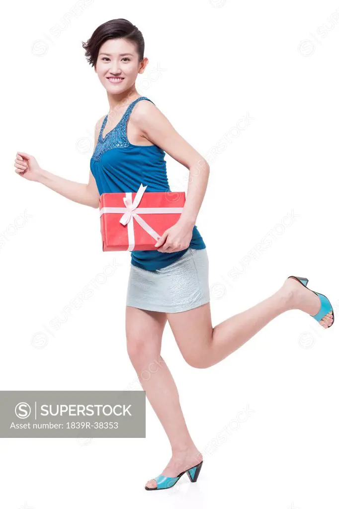 Cheerful young woman running with gift in hand