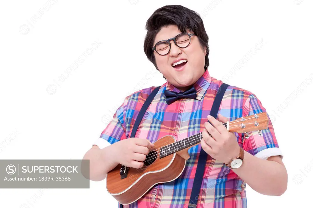 Happy overweight man playing small guitar and singing
