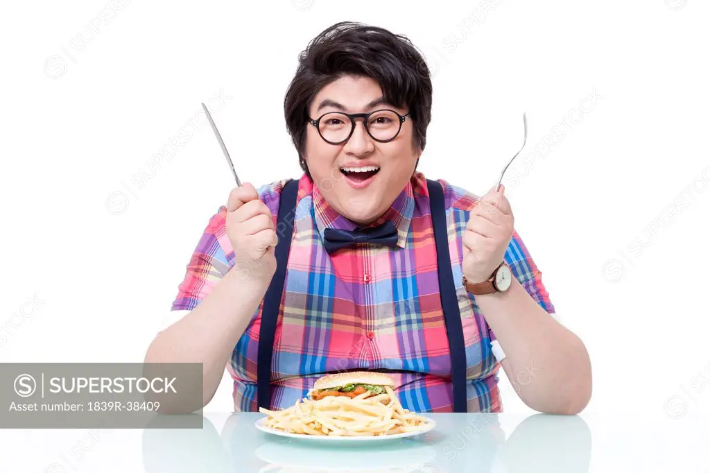 Happy overweight man enjoying burger and chips