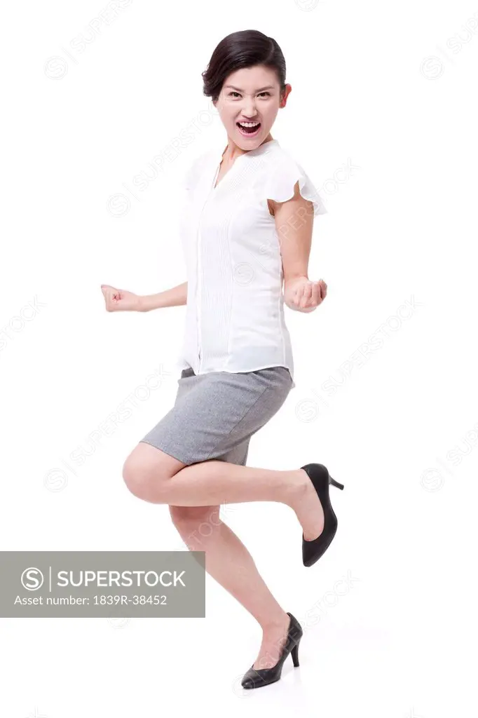 Excited businesswoman standing on one leg