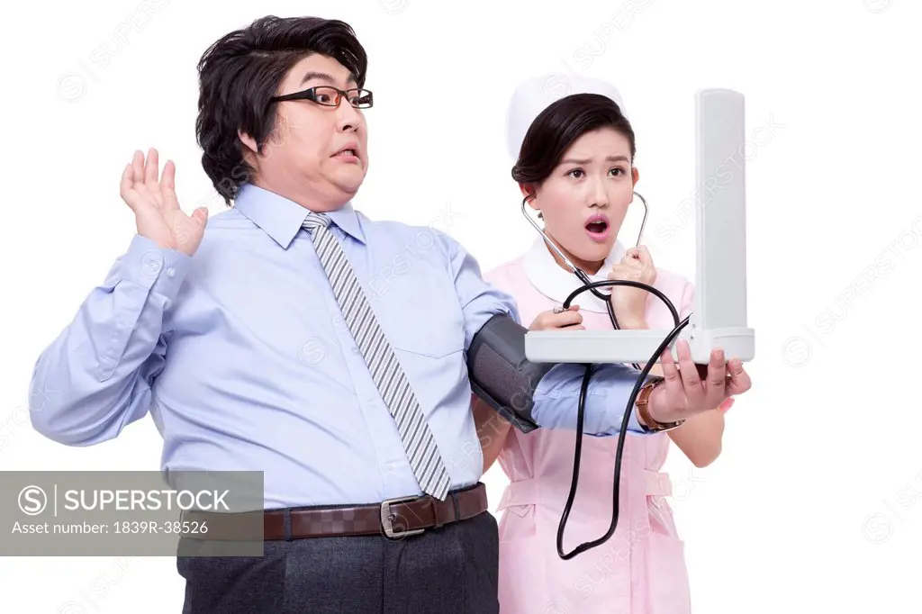 Nurse measuring blood pressure for overweight businessman
