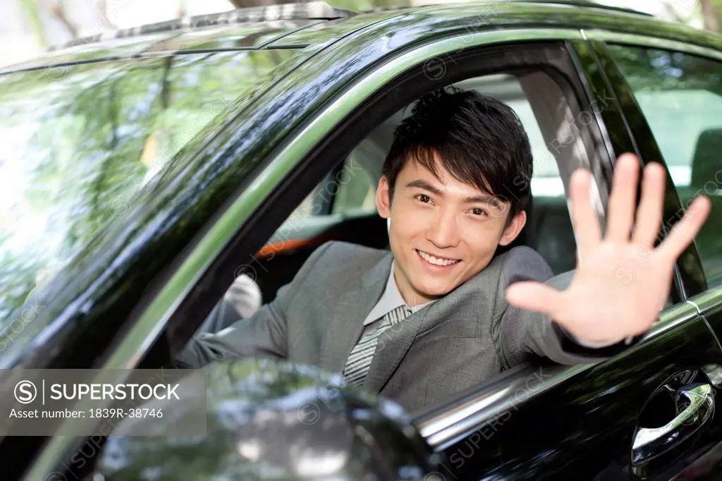 Businessman waving inside car