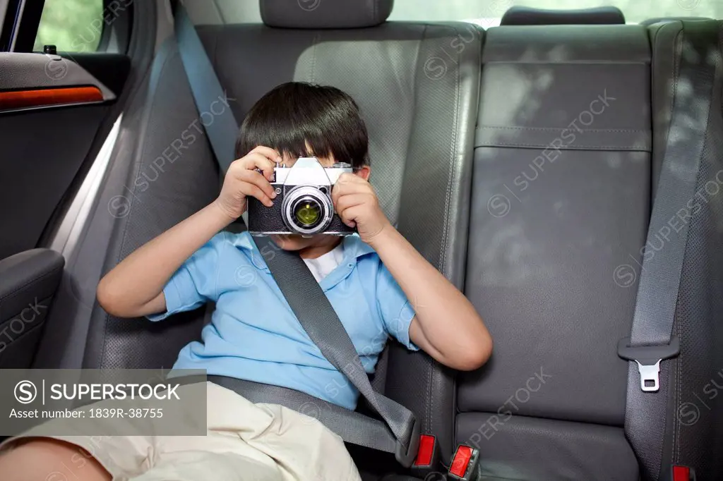 Young boy in back seat photographing with a camera