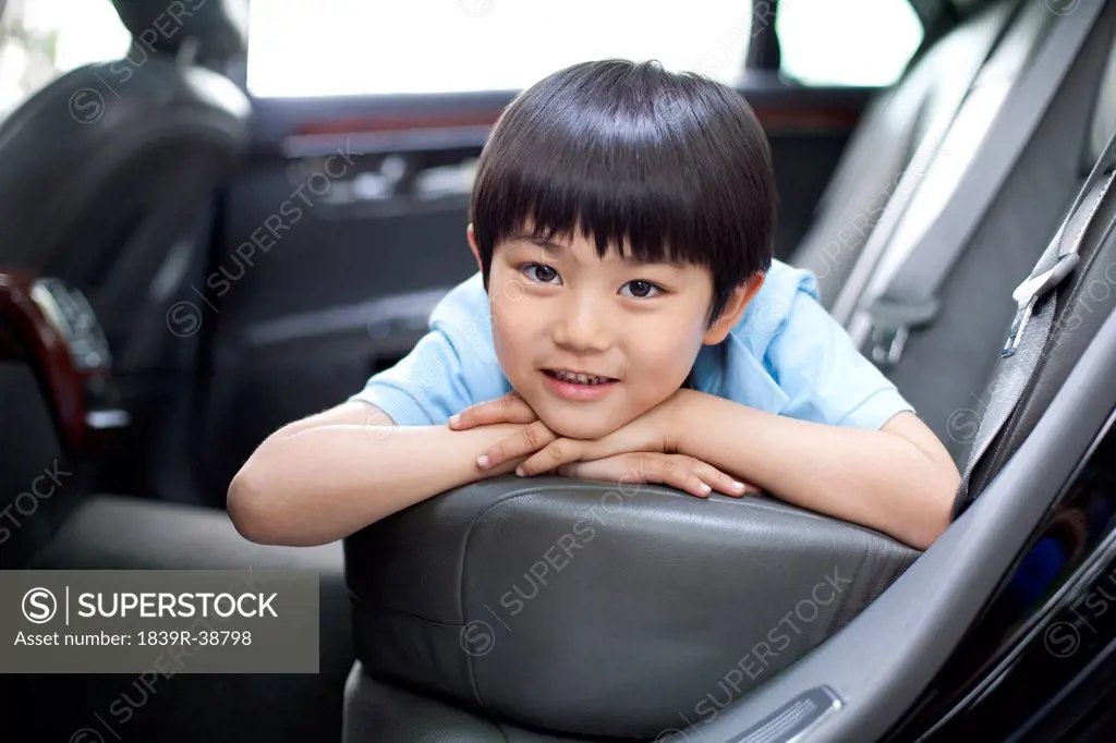 Happy boy lying in car back seat